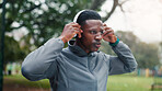 Fitness, man and tired with headphones at park for running challenge, workout music and cardio with sound playlist. Black person, rest and streaming radio for exercise break, morning jog and fatigue