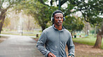 Fitness, man and running with headphones at park for cardio challenge, breathing and marathon training with music. Black person, athlete and listening to podcast for exercise, morning jog or wellness