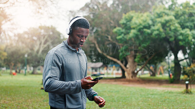 Buy stock photo Athlete, man and phone with headphones at park for fitness music, audio playlist and cardio challenge with sound. Black person, runner and streaming service for marathon training, exercise or workout