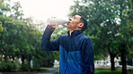 Drinking water, outdoor and man with fitness, healthy guy and training with thirsty. Person, athlete and runner in street, bottle and liquid with wellness, hydration and sports with exercise