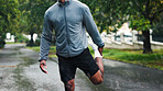 Fitness, person and stretching leg outdoor for running performance, start workout and getting ready. Rain, athlete and cardio warm up in road for muscle strength, training and exercise preparation