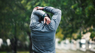 Buy stock photo Back, fitness and athlete with arm stretching outdoor for workout performance, muscle strength and wellness. Rain, person and start warm up at park for cardio exercise, sports training or preparation