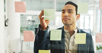 Buy stock photo Creative, man and writing on sticky notes by glass wall for campaign planning, budget development and ideas. Marketing manager, employee and calendar tasks for project management or business strategy