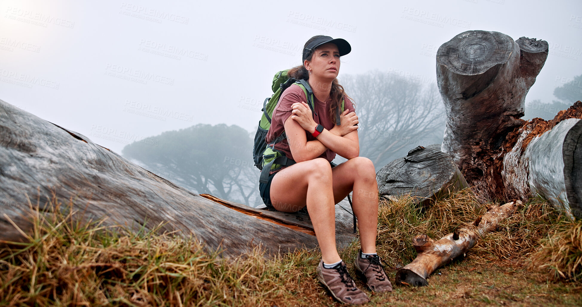 Buy stock photo Girl, hiking and getting cold on mountain in winter, thinking and fatigue with weather change, fog and tourism. Person, woman and trekking on tree trunk, exhausted and tired on adventure in Argentina