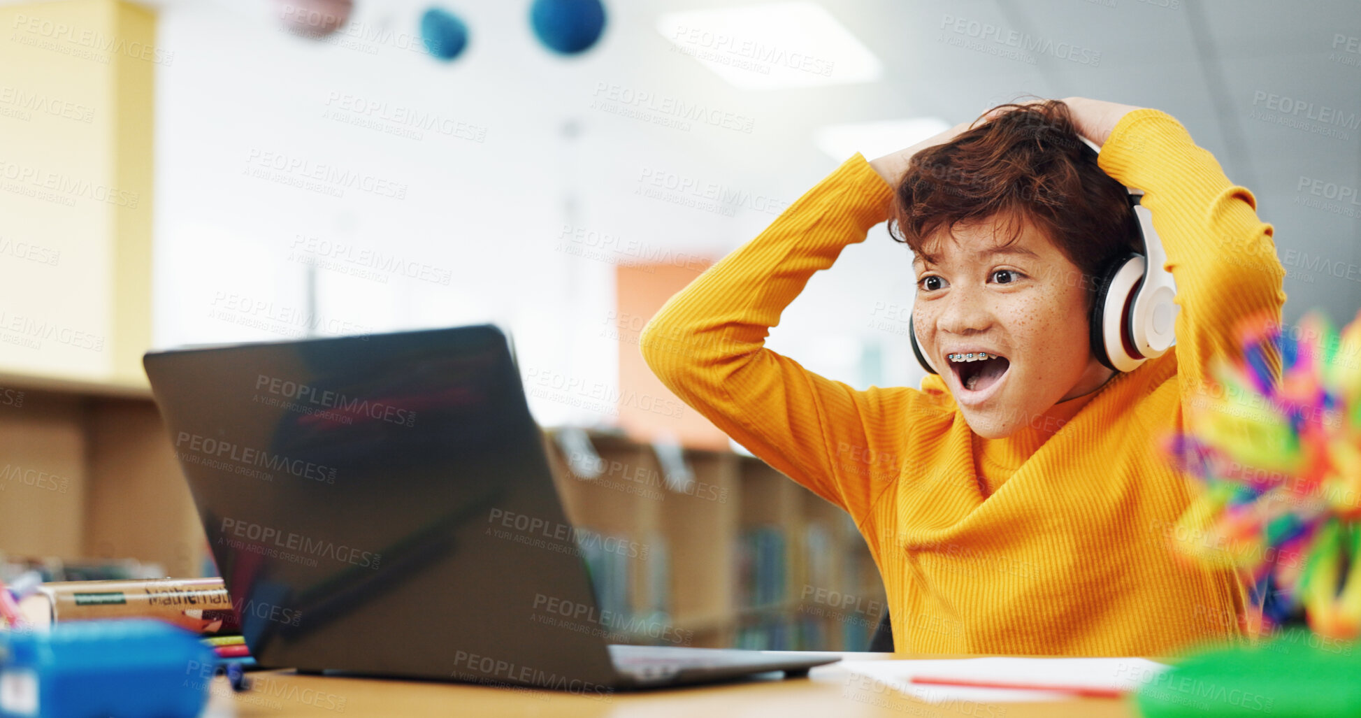 Buy stock photo Happy child, student or good news with laptop for winning, elearning or grade results in library. Boy, kid or excited learner with wow, headphones or computer for online score or educational progress