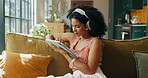 Tablet, headphones and woman on sofa for music, streaming song or audiobook in home. Living room, technology and African person listening to radio, podcast and sound for playlist on internet to relax