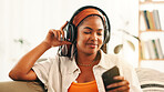 Headphones, happy woman and relax with mobile on sofa with podcast, audiobook or sound. African person, music and phone for streaming radio, subscription or listen to favorite song for peace in home