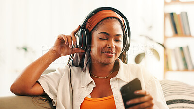 Buy stock photo Headphones, happy woman and relax with mobile on sofa with podcast, audiobook or sound. African person, music and phone for streaming radio, subscription or listen to favorite song for peace in home