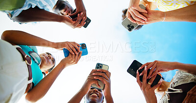 Buy stock photo Below, hands and people with cellphone, outdoor and smile with connection, social media or group. Blue sky, low angle or friends with closeup, smartphone or tech for message, texting or communication