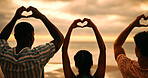 Group, heart hands and friends by sunset, ocean and back with connection for love with care by sea. People, together and community for symbol, sign or support with kindness on vacation at beach