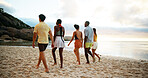 Back view, vacation and friends walking on beach for holiday or summer trip on tropical island together at sunset. Group, tourism and people at ocean for relax, bonding and travel on adventure at sea