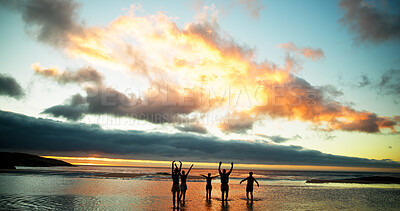 Buy stock photo Sunset, freedom and friends in sea water for holiday, vacation and summer trip on tropical island. Group, ocean and people in celebration by beach for travel, adventure and hands up together at dusk