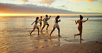 Buy stock photo Sunset, running and friends in sea water for holiday, vacation and summer trip on tropical island. Group, ocean and people race by beach with energy for freedom, travel and excited for adventure