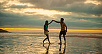 Couple, dance and holding hands for fun on beach of travel date, romance and sunset of summer holiday. People, playful and bonding on vacation trip, tropical island and partner commitment of getaway 