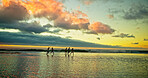 Sunset, people running and friends in sea water for holiday, vacation and summer trip on tropical island. Group, ocean and race by beach with freedom for travel, adventure and energy with space