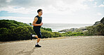 Ocean, running and man in street, fitness and sports with cardio, workout and challenge. View, person and runner with exercise, outdoor and energy with wellness, practice and healthy with training