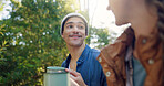Outdoor, camping and couple with coffee, smile and bonding with warm beverage in nature and adventure. Forest, travel and people with hot tea for cold weather, traveller and tourists on vacation