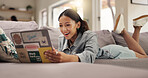 Happy woman, student or good news with laptop on sofa for college application or acceptance at home. Female person, smile or lying with computer on couch for academic result or online course at house
