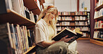 Student, reading and book on floor in library for learning, financial study and business course. Woman, finance textbook and knowledge for investment information, education exam and advice for growth