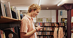 Smile, man and student with phone in library for communication, social media and message update. Male person, mobile and education search at academy for campus gossip, online post and notification