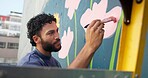 Man, painting and design in city at wall art, creative mural and project to uplift community. Volunteer, creativity and outdoor with smile for floral decor, social responsibility and DIY hobby