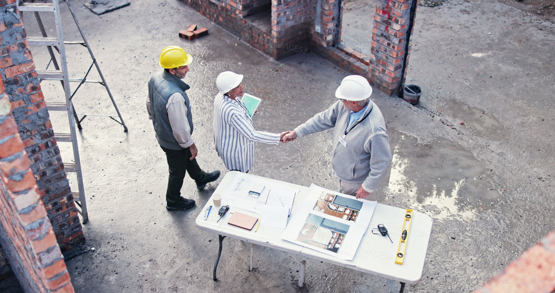 Buy stock photo Team, handshake and people on construction site for plan, inspection or collaboration at table. Contractor, welcome and woman with tablet for blueprint, brainstorming or architect design from above