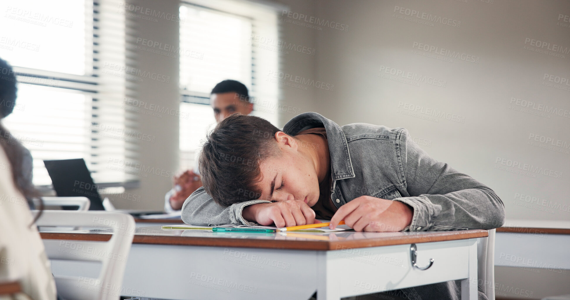 Buy stock photo Tired, school and boy in classroom at desk with fatigue for writing assignment, test and quiz. College, university and exhausted student sleeping for learning, education and bored in lesson on campus