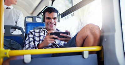 Buy stock photo Happy man, bus and playing games with phone for travel, local commute or entertainment in city. Male person, traveler or mobile gamer with smile or headphones for online streaming in public transport