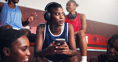 Buy stock photo Woman, phone and break on basketball court with music, podcast or connectivity with team. African athlete, headphones or thinking on benches with mobile, sports audio and relax in tournament for rest