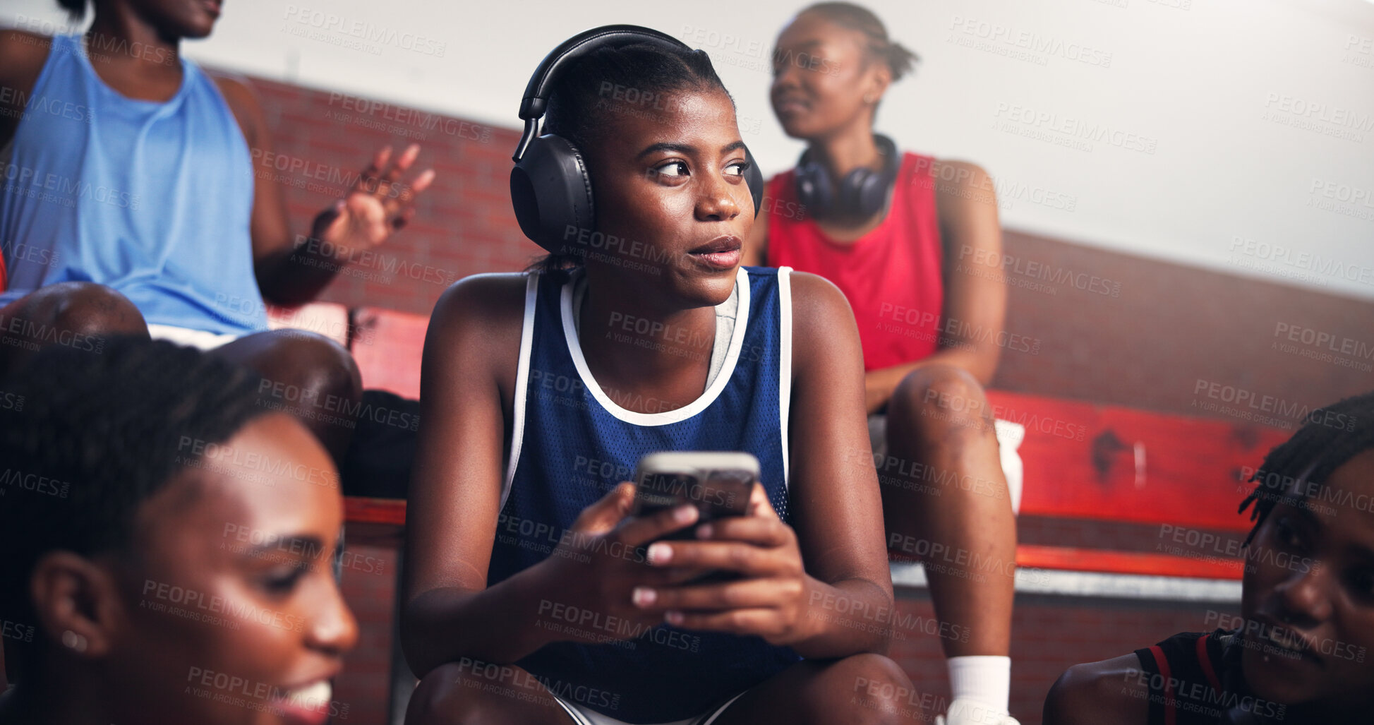 Buy stock photo Woman, phone and break on basketball court with music, podcast or connectivity with team. African athlete, headphones or thinking on benches with mobile, sports audio and relax in tournament for rest