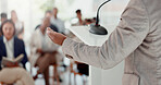 Businessperson, hand and back of speaker in seminar for education, event or presentation. Conference, microphone or corporate coach with forum speech on podium for public relations or development