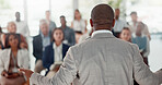 Businessman, talking and back of speaker in seminar room for education, event or presentation. Conference, audience or corporate coach with forum speech on podium for public relations or development