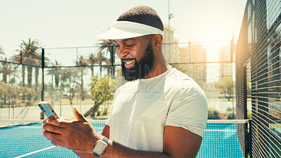Buy stock photo Man, phone and happy at tennis court for sport, texting or contact on break for training in summer. African person, athlete and smartphone on mobile app, smile or social media with fitness in Kenya