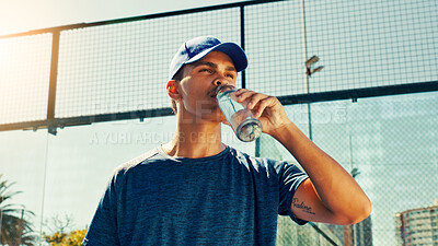 Buy stock photo Sports, drinking water and man on tennis court rest for hydration, thirst and wellness outdoors. Fitness, athlete and person with bottle after training, exercise and workout for padel practice