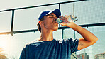 Sports, drinking water and man on tennis court on break for hydration, thirst and wellness outdoors. Fitness, athlete and person with bottle after training, exercise and workout for padel practice
