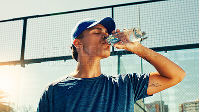 Buy stock photo Sports, drinking water and man on tennis court on break for hydration, thirst and wellness outdoor. Fitness, athlete and person with bottle after training, exercise and workout for game or practice