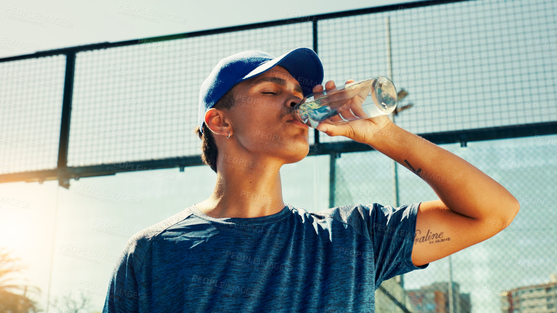 Buy stock photo Sports, drinking water and man on tennis court on break for hydration, thirst and wellness outdoor. Fitness, athlete and person with bottle after training, exercise and workout for game or practice