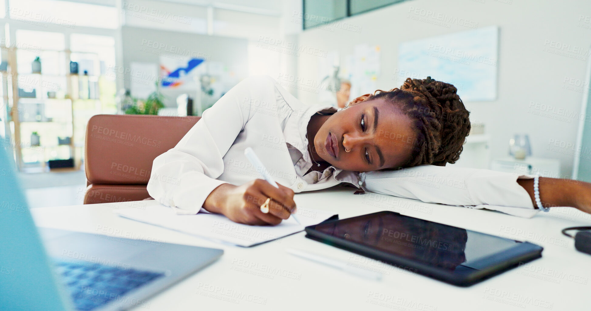 Buy stock photo Bored, black woman and writing with fatigue for burnout, stress or insomnia at office desk. Tired, female person or lazy employee taking notes by technology for procrastination or sluggish work ethic
