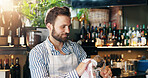 Barman, happy and shine glass with cloth for hygiene, dust and service for drinks at restaurant. Person, bartender and cleaning for dirt with smile, job and career with reflection at small business