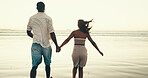 Back, couple and holding hands for walk on beach of summer vacation, romantic date and bonding. People, journey and travel for tropical holiday, partner affection and relationship commitment at ocean