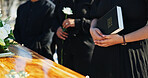 Bible, praying and family by coffin at funeral for respect, blessing or spiritual comfort at graveyard. Religion, prayer and people by casket with white rose and holy book for grief, loss or farewell