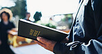Bible, church and hands of priest at funeral for respect, ceremony or spiritual farewell. Grief, worship and pastor with holy book for memorial service at burial for mourning with religious comfort.