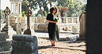 Sad, woman and mourning with flowers at cemetery for death ceremony, memorial service or funeral. Burial, person or floral bouquet by tombstone for goodbye, loss and grieving with remembrance or pain
