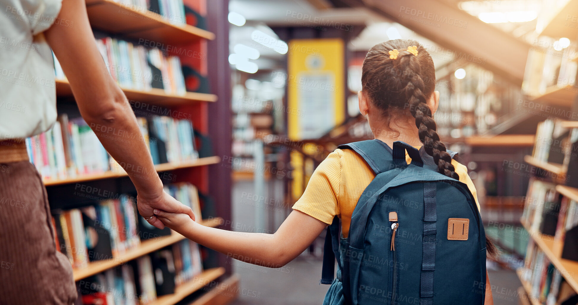 Buy stock photo Education, tutor and child in library, holding hands and walking with student, bookshelf and back. Knowledge, growth and development of kid with books, learning and teacher with girl in school