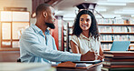 University, talking and students in library on laptop for online research, information and studying for project. College, academy and man and woman with books for education, knowledge and learning