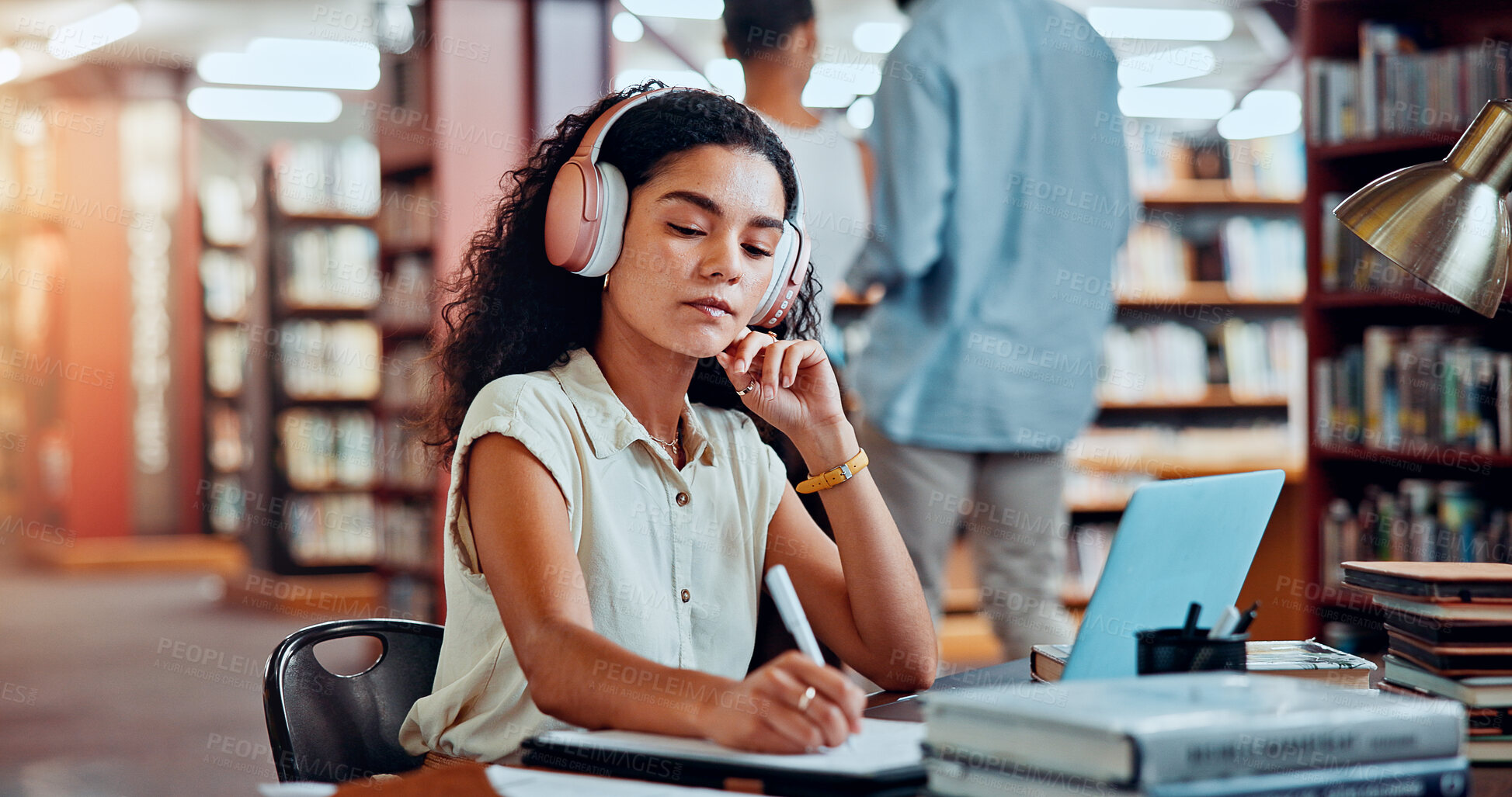 Buy stock photo Student, headphones and writing in library for university, woman and studying for education or project. Female person, notes and academy campus with literature, research and assignment for knowledge