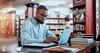 Buy stock photo University, books and man in library on laptop for online research, information and studying for project. College, student and person with computer and notes for education, knowledge and learning