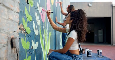 Buy stock photo Girl, teamwork or artists painting on wall for mural, drawing flowers or community service at building. People, creative or women with brush for floral decoration, renovation or project for design 