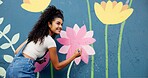 Woman, excited or artist painting on wall for mural, drawing flowers or community service at building. Smile, outdoor or happy girl with color for floral decoration, renovation or project for design