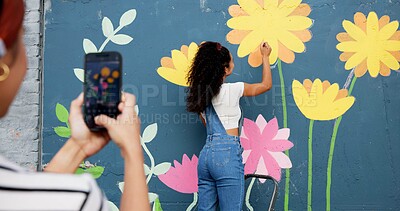Buy stock photo Painting, wall and people with picture, outdoor and phone screen with art, flowers and decor for mural. Photography, painter and creative for community project, social media and women with mobile app